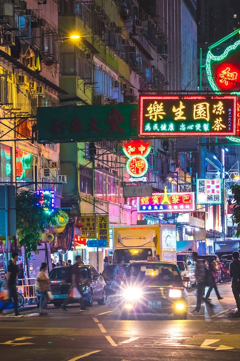 Colorful neon lights illuminate a bustling street in the New Territories, Hong Kong, by night.