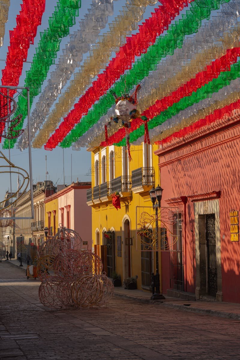 Vibrant street in Oaxaca decorated with festive red, green, and white streamers.